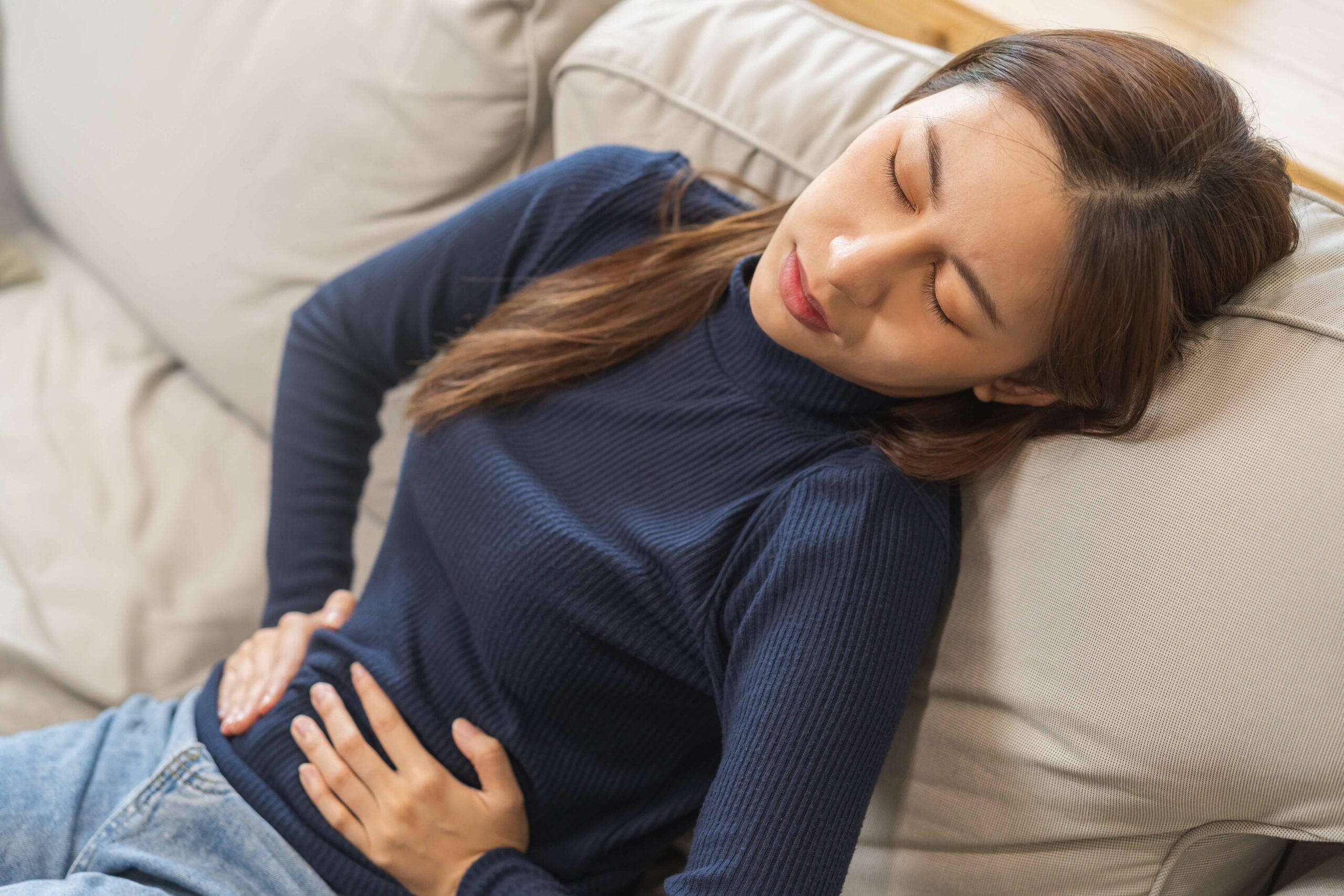 Young female experiencing abdominal pain—she is concerned and unsure if it may be due to miscarriage, implantation bleeding, or just her period